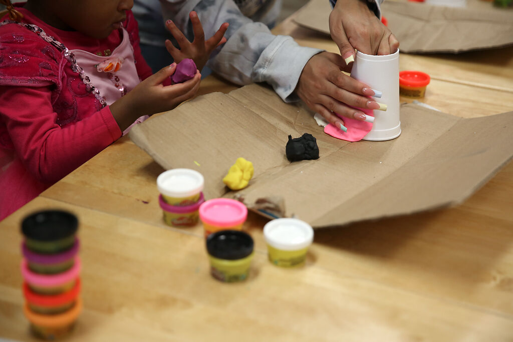 Serenity Cave helps a child staying at Rainbow House pack Play-Doh